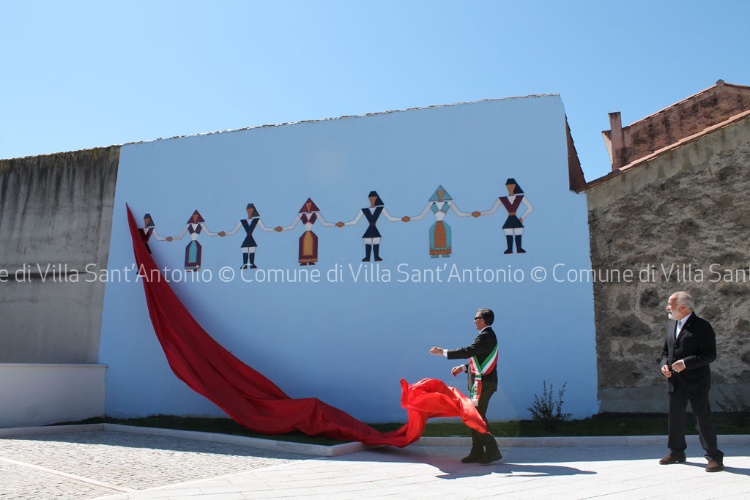 Scultura in ceramica smaltata di m 10x1 su parete dipinta in celeste, raffigurante un ballo sardo